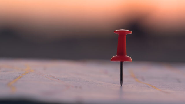Close up red pin push map under sunset background. business focu